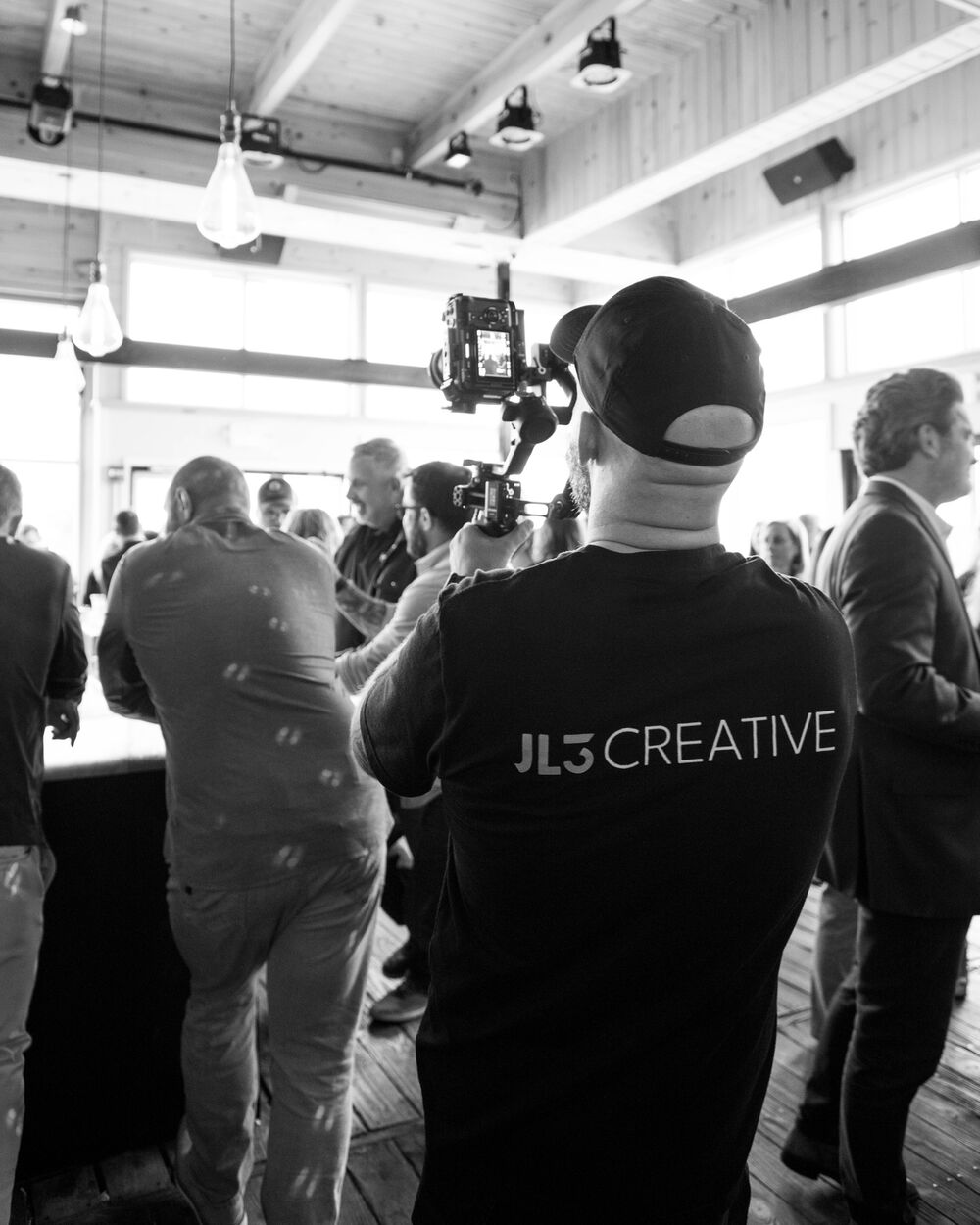 James filming guests at an event, JL3 Creative shirt on his back